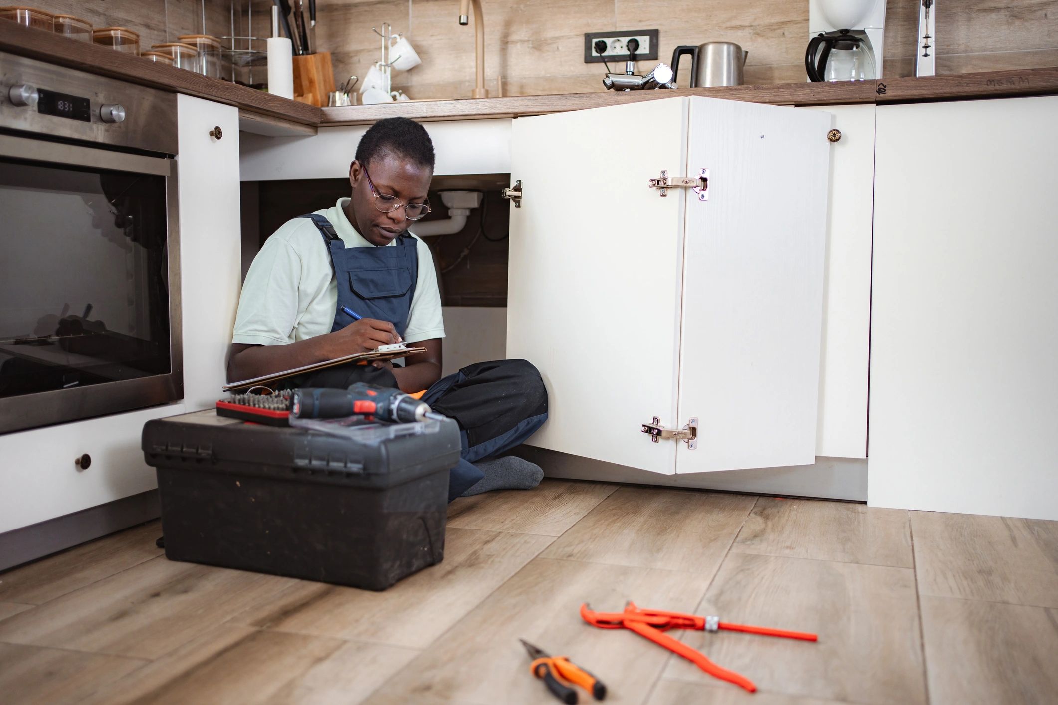 Plumber inspecting pipes under a kitchen sink
